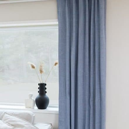 Pleated drapery cascade against tall windows